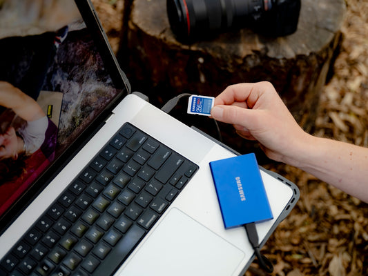 A person holding a camera and a laptop