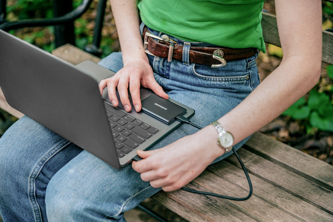 A woman sitting on a bench with a laptop