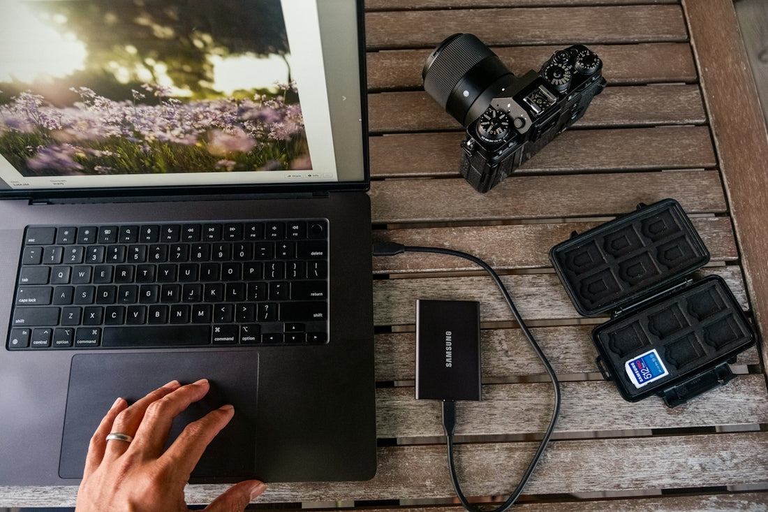Laptop, camera, and memory card reader on wooden table