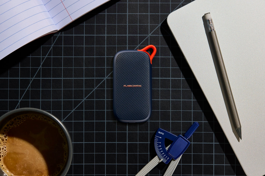 Portable ssd, coffee, and stationery on a grid mat.